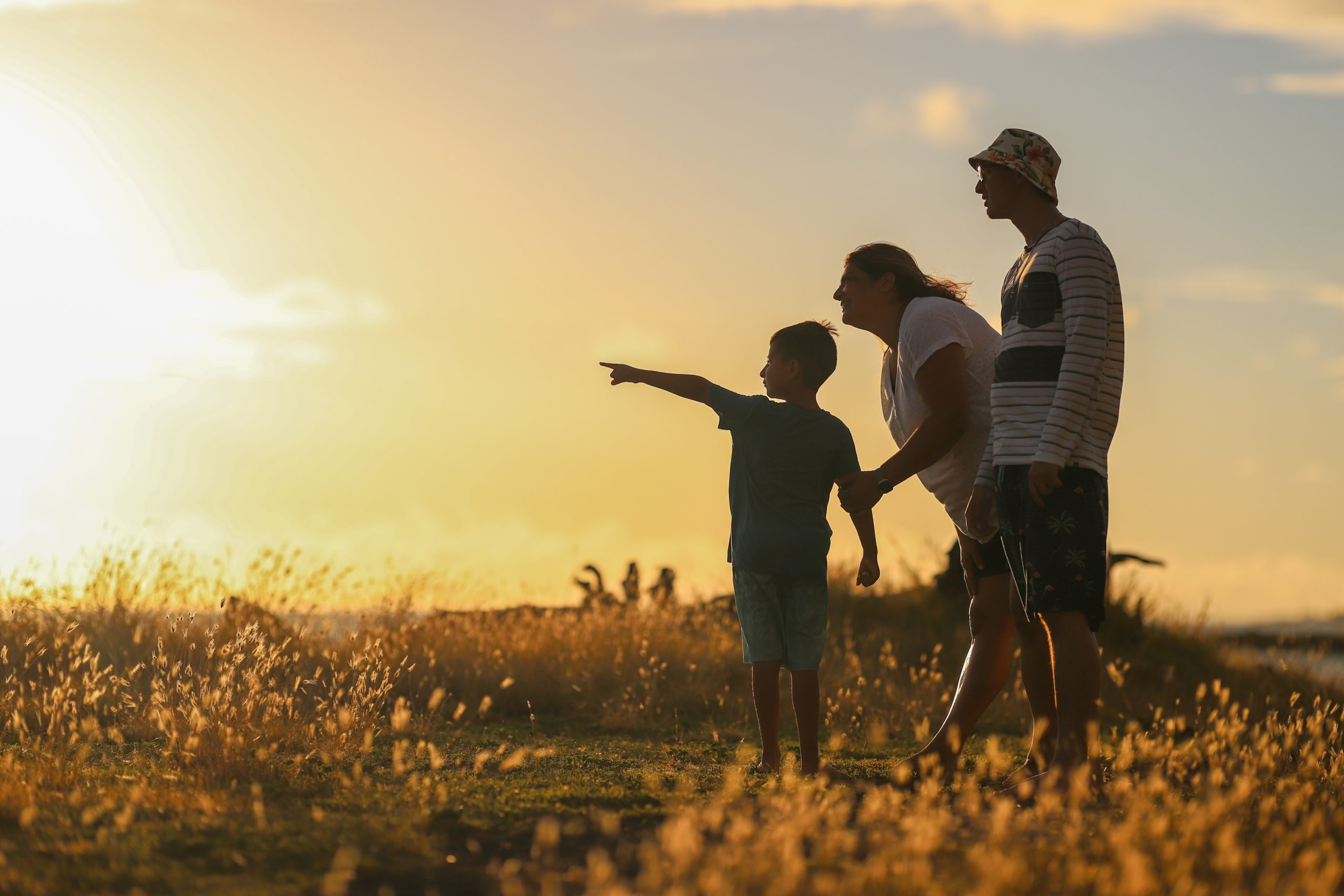 Family of 3 standing in a field at golden hour